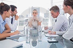 Serious businesswoman looking at camera with colleagues around