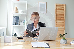 Serious businesswoman looking at her notebook in office