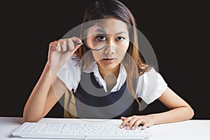 Serious businesswoman looking through magnifying glass