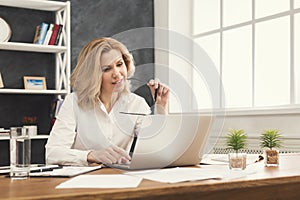 Serious businesswoman working on laptop at office