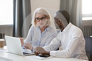 Serious busy aged mentor helping to new african employee