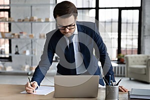 Serious busy business leader signing legal document at workplace