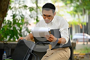 Serious busy businessman sitting on his bicycle and checking business documents