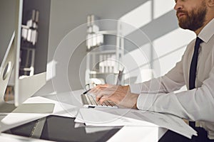 Work online. Serious busy businessman reads working documents sitting at a table with a computer in the office.