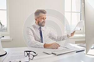 Serious busy businessman working documents sitting at a table with a computer in the office.