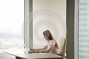 Serious busy woman working on laptop in office interior, copyspa