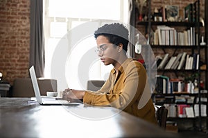 Serious busy young Black laptop user woman working at computer