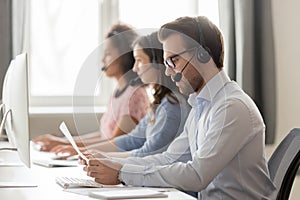 Serious call center agent in headset reading paper documents
