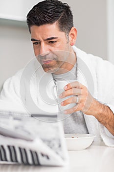 Serious casual man with coffee cup reading newspaper photo