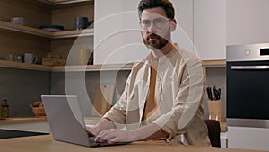 Serious Caucasian man browsing internet service chatting online in social media renter with laptop at kitchen food