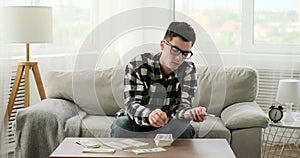 Serious Caucasian Man Counts Cash on Living Room Sofa