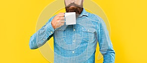 Serious caucasian man crop view holding tea mug yellow background