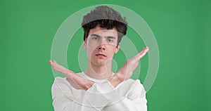 Serious Caucasian Man Crossing Arms in Stop Gesture on Green Background