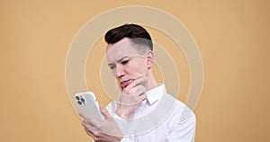 Serious Caucasian Man Engaged with Phone on Beige Background