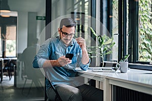 Serious caucasian man with glasses, getting a message on phone
