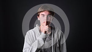 Serious Caucasian Man Making shush Gesture on black Background