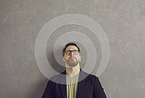 Serious caucasian man with a pensive and dubious expression looks up over his head.