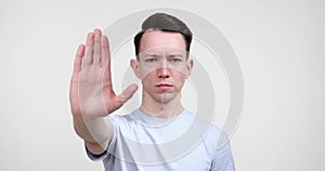 Serious Caucasian Man Showing Stop Gesture on White Background