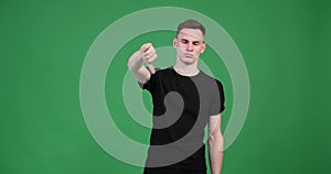 Serious caucasian man showing thumbs down on green background