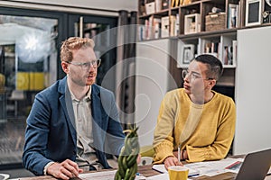 Serious caucasian man, talking to his curious female coworker