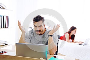 Serious Caucasian man and wife working with online shopping business on laptop in social media technology together in bedroom.