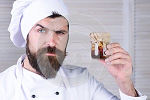 Serious chef with jar of honey nuts. Healthy breakfast. Bearded man in chef uniform with honeyed assorted nuts in glass