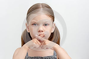 Serious child crossed fingers on mouth