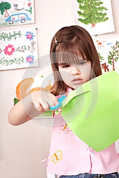 Serious child cutting paper.