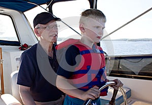 A serious child learns sailing from his grandfather