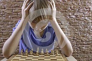 Serious clever boy looking at chess board