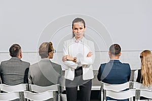 serious coach with crossed arms looking at camera during business training