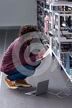 serious computer engineer working while sitting on floor at cryptocurrency