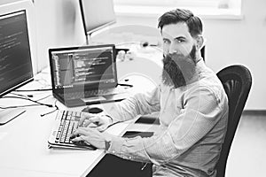 Serious computer programmer developer working in IT office, sitting at desk and coding, working on a project in software