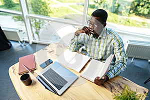 Serious concentrated african man studying or working with laptop indoors