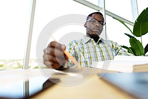 Serious concentrated african man studying or working with laptop indoors