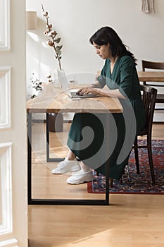 Serious concentrated businesswoman working at desk on laptop