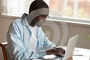 Serious concentrated young african american man working remotely with computer.