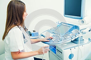 Serious, concentrated young doctor, specialist using Ultrasound Scanning Machine for pacient testing. Copy space. Selective focus