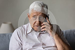 Serious concerned old grandpa talking on mobile phone