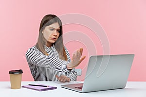 Serious concerned woman office worker showing stop gesture to laptop screen, warning with prohibition sign talking on video call,