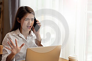 Serious concerned Young Asian business woman arguing while talking on phone