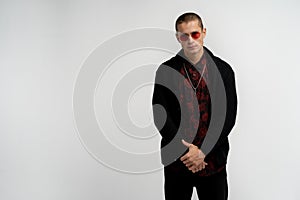 Serious confident attractive young man with short haircut in red sunglasses wearing stylish black sweater and shirt