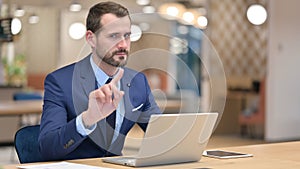 Serious Middle Aged Businessman with Laptop saying No with Finger Sign photo