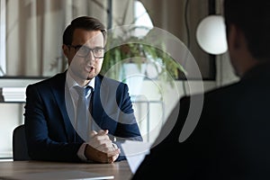 Serious confident employer and candidate sitting opposite at job interview