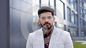 Serious confident Indian man with deep gaze looking at camera outdoor.