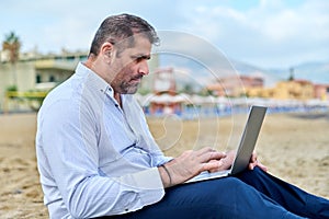 Serious confident mature man with laptop outdoors