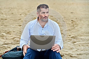 Serious confident mature man with laptop outdoors