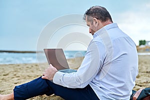 Serious confident mature man with laptop outdoors