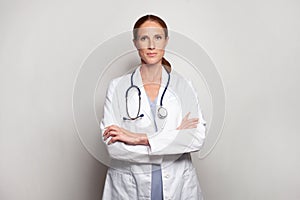 Serious confident medical professional in white lab coat standing against studio wall banner background