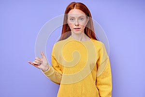 serious confident redhead woman in yellow stylish sweater demonstrating letter Y